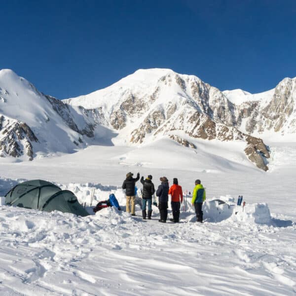 Risk Management on the Mountain. Group standing at the base of a snowy mountain planning their expedition.